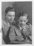 Two radio announcers pose next to a microphone